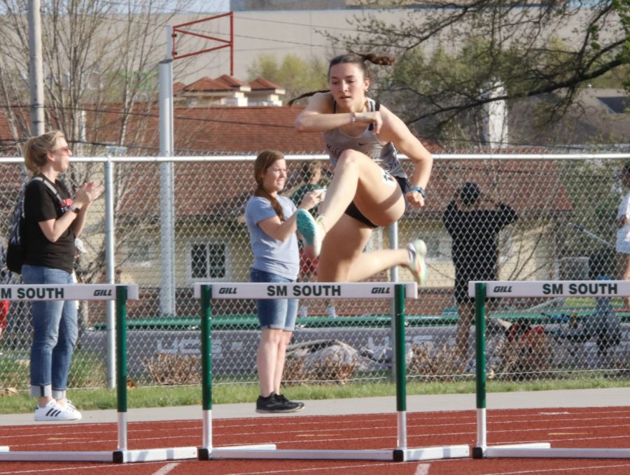 In mid-air, senior Quincy Hubert leaps over a hurdle to clear it during the 300 meter hurdle race. Hubert, who broke her own school record in the 100 meter hurdles, took first place in the 300 meter hurdle race with a time of 46.22 seconds; four seconds ahead of second place Olathe Northwest finisher Olivia Cooper. 