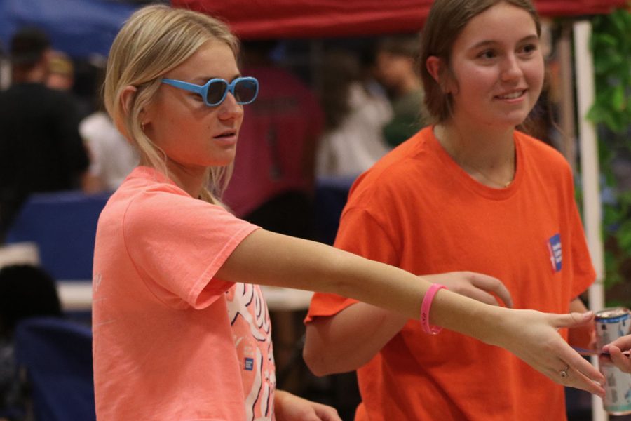 Stretching out her arm, sophomore Taylor Hey collects tickets for her Hungry Hungry Hippo-themed booth.