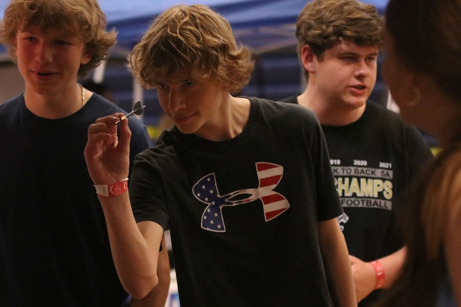 Eyes locked on his target, sophomore Noah Brueggmann attempts to pop a balloon with a dart in order to win a prize.