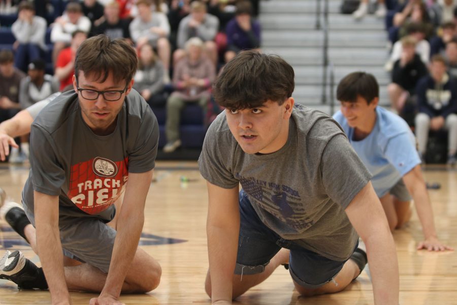 Crawling on the floor, senior Ryan Pasley participates in the silver studs performance Friday, April 1.
