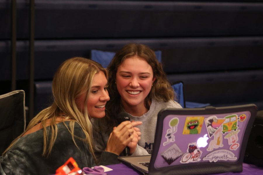 Microphone in hand, senior Shelby Easum and junior Cadence Mayhugh sing karaoke at their booth Saturday, April 23.