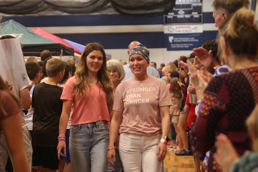 Walking the survivor lap, sophomore Brynn Shideler walks beside her mom, Amy Shideler, Saturday, April 23 as the crowd cheers them on.