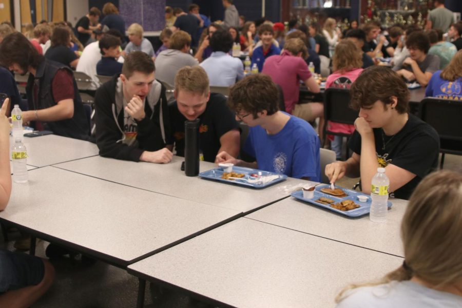Leaning toward each other, seniors Ty Allenbrand, Braden Spieker, Patrick Mack and Gabriel Joyce watch one person’s phone as they eat breakfast.  