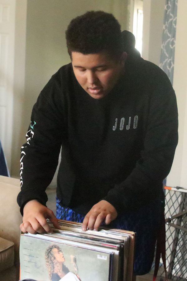 In his living room, senior Damon Standen-Loyd sorts through his vinyl collection.