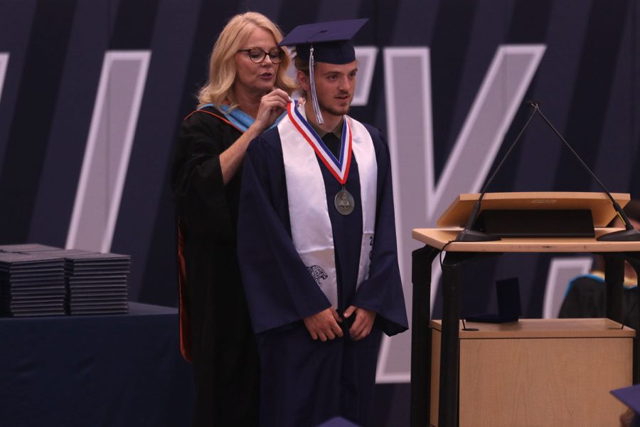 On stage, senior Luke Hoelting is presented with the valedictorian medal by principal Dr. Gail Holder. 