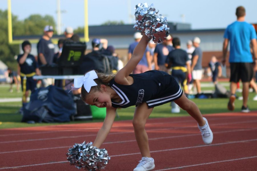 With a smile on her face, an elementary school cheerleader begins her cartwheel.