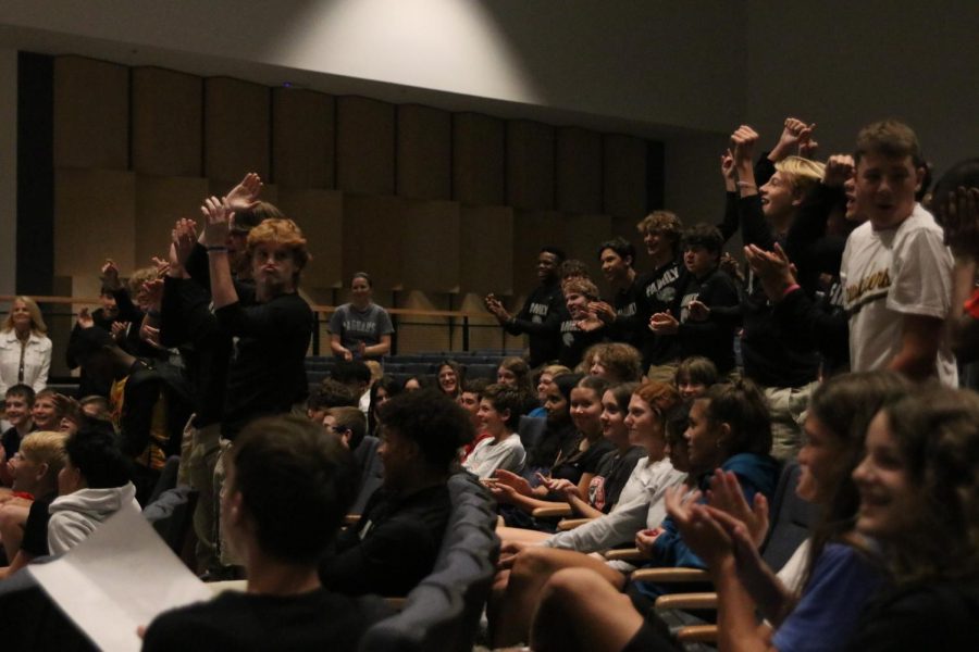 Upon the announcement of the next candidate speech, a group of freshman boys stand up to cheer.