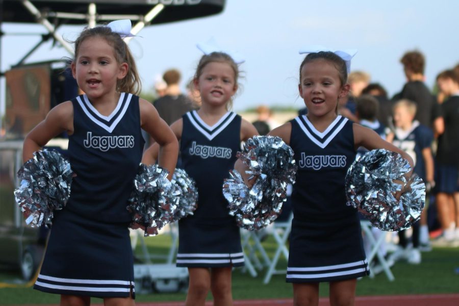 With their hands on their hips, a group of elementary school cheerleaders cheer during the scrimmage. 