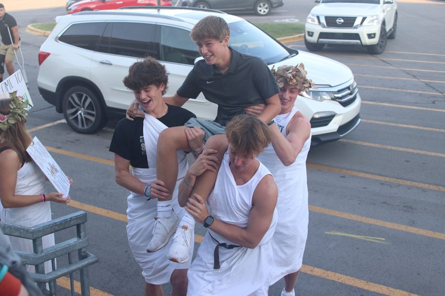 Coming up the stairs, seniors Hayden Jay, Collin Schroeder and sophomore Connor Bohon carry an incoming freshman into the school. 