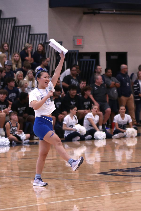 Commencing the Homecoming pep assembly, senior StuCo representative Sophia Chang raises an arm and leg in the air.
