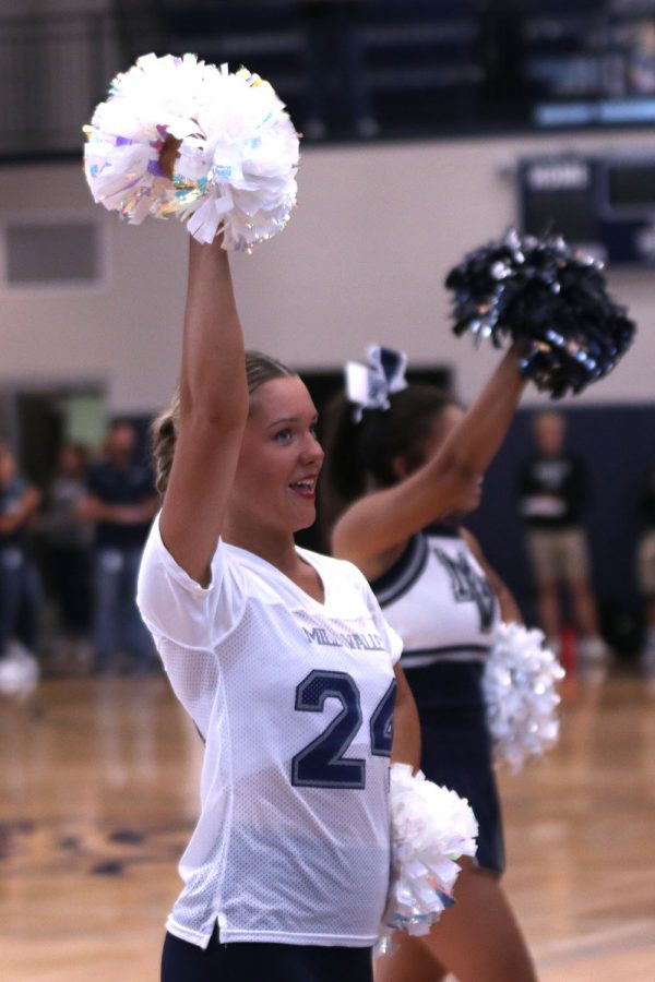Looking into the crowd, junior Macy Bidnick waves a pom in the air.
