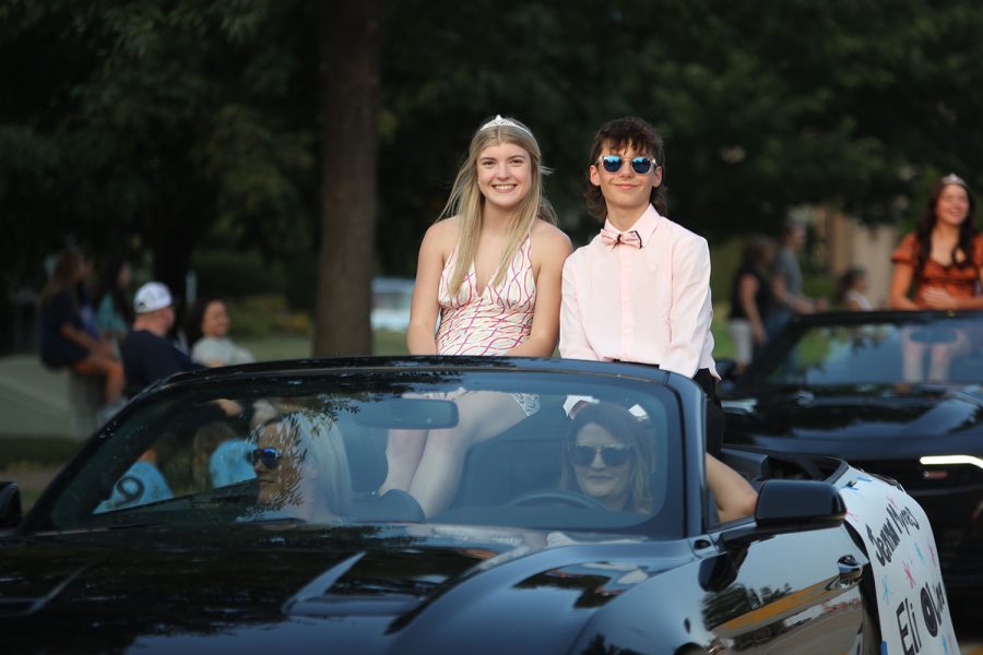 Riding in the back of a convertable, Senior Homecoming candidates Jenna Myres and Eli Olson smile at the camera.