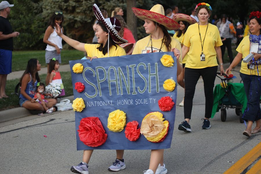 Waving to the crowd, Spanish National Honors Society members seniors Sophia Chang and Adisyn Hopkins hold a poster together.
