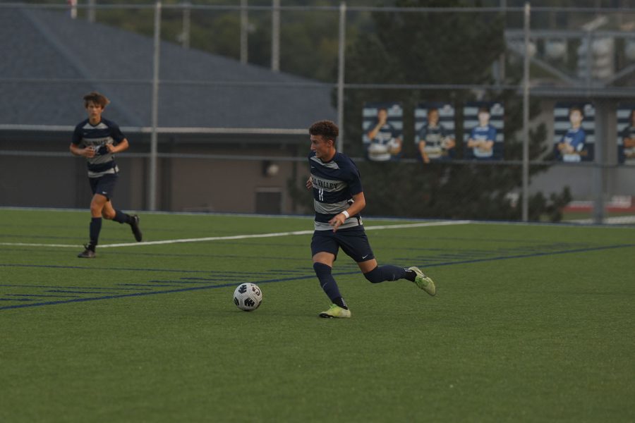 On the side of the field, senior Dylan Ashford dribbles the ball.