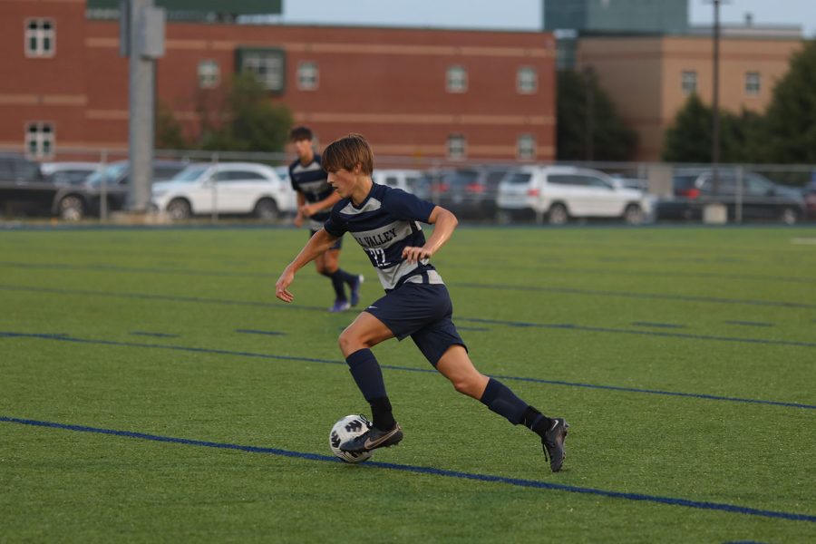 Moving towards the middle of the field, sophomore Brady Robins dribbles the ball. 
