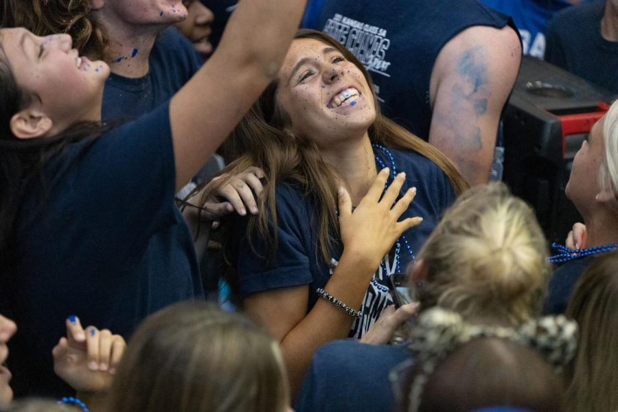 Singing alongside her friends, senior Sidney Claeys smiles wide with blue paint all over her. 
