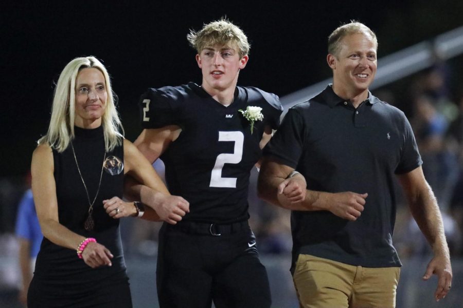 Alongside his parents, senior Homecoming candidate Hayden Jay walks toward his fellow nominee for the crowning ceremony. 