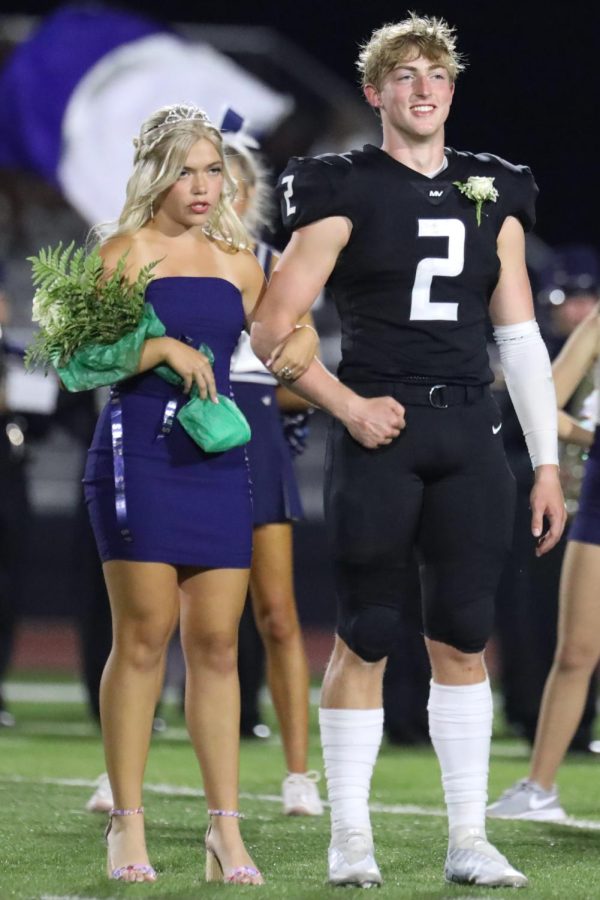 Waiting for the announcer to share who won Homecoming court, senior Homecoming candidates Hayden Jay and Bri Coup smile on the field. 