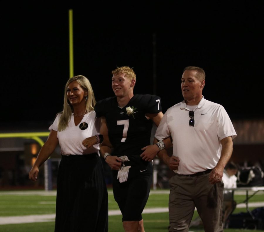 Senior Homecoming candidate Mikey Bergeron and his parents walk together during the coronation ceremony.