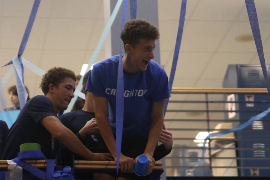 Leaning over the edge of the stairs, senior Dylan Ashford looks down at the foyer with an excited look on his face.