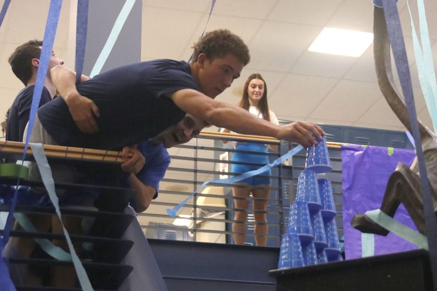 Focused on completing his tower of cups, senior Luke Shideler leans over the railing.