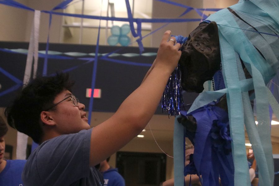 Looking up at the jaguar statue, senior Justin Sivilayvong adds a pom pom to it.