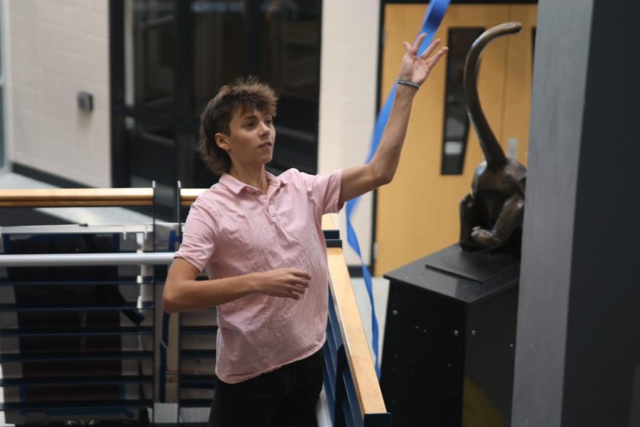 Following through with his throw, senior Eli Olson watches where his blue streamer lands in the senior hallway.