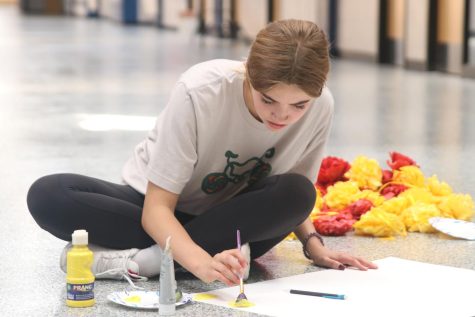 Focused on painting her poster, freshman Claire Cooper uses yellow paint to create a poster for her grades locker bank.