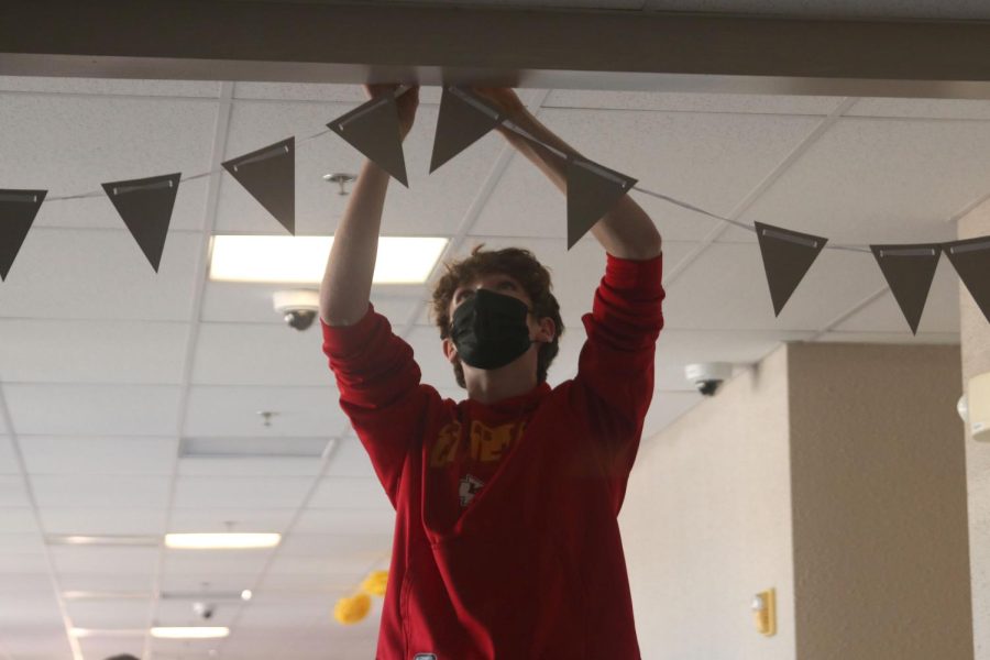 Hanging up a decoration, freshman Gabe Sommerfeld helps decorate the freshmen hallway.