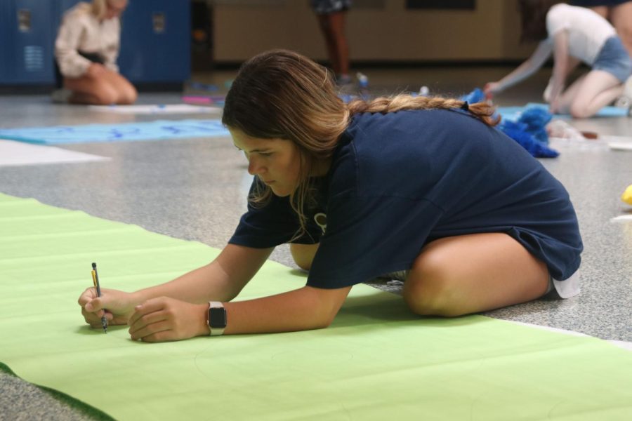 While sitting on the floor, sophomore Brynn Shideler writes out the phrase “soph stars” to decorate the hallway.