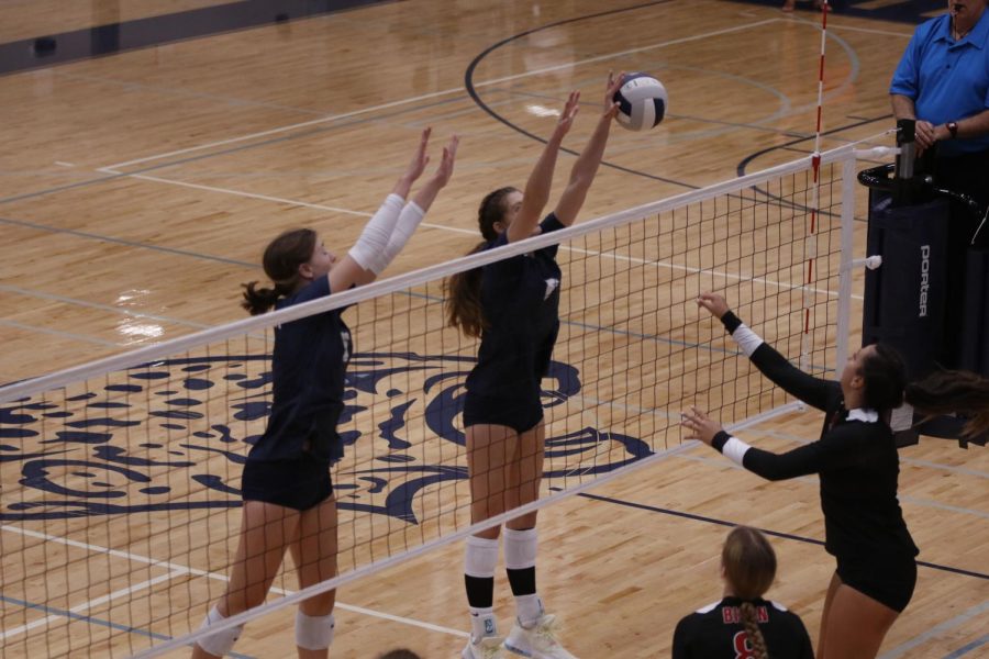 Working together, junior Kaitlyn Burke and sophomore Saida Jacobs block the Shawnee Mission North point. 
