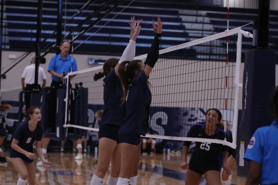 Moving in sync, freshman Ella Florez and sophomore Saida Jacobs jump up to block the Olathe South hitter. 