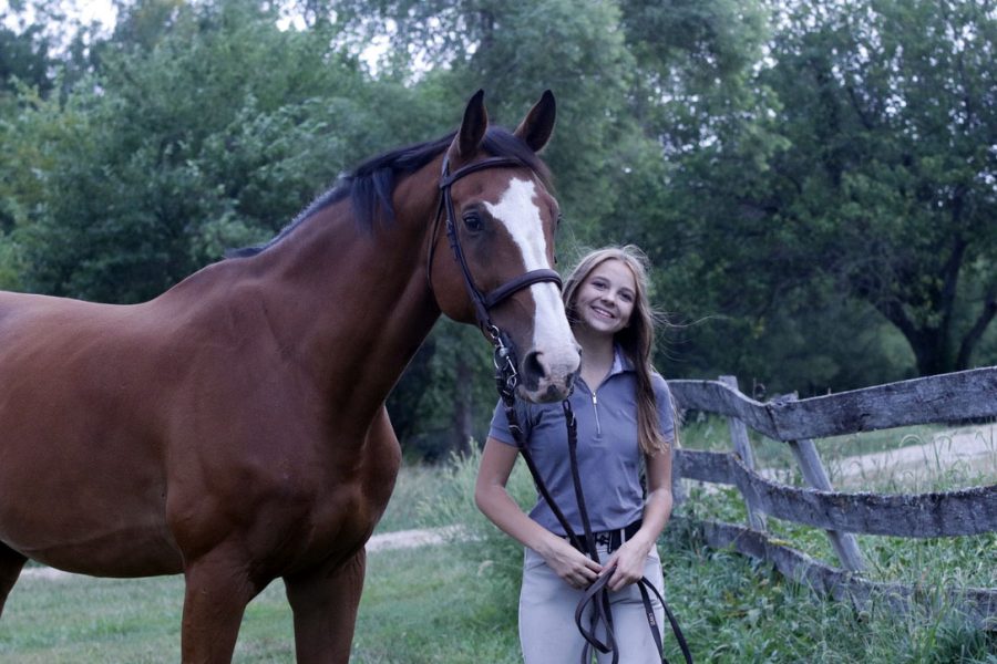 Freshman Sarah Allerheiligan stands and smiles next to her new horse, Luke, outside of where she practices Sunday, Sept 11.