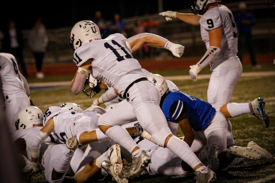 Ball in hand, defensive back senior Mark Bauer runs past the mound of players to gain yardage on the play.