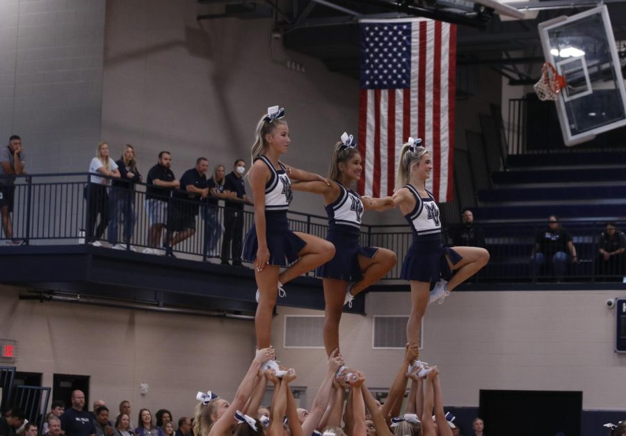 Senior Lucy Pearce, sophomore Emersyn Jones, and freshman Sydney Epperson perform a stunt during the pep assembly.