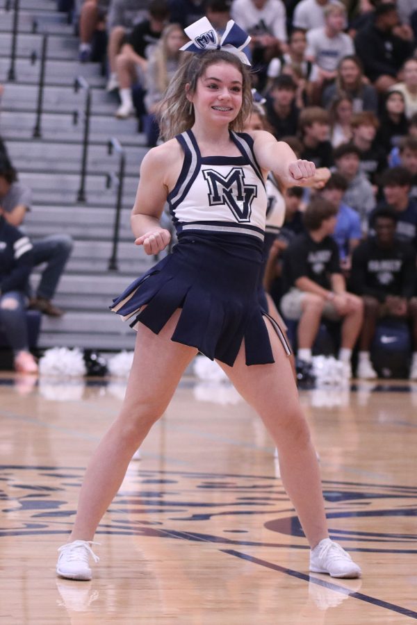 With her hand in a fist, sophomore cheerleader Rylie Maguire poses during the cheer performance.