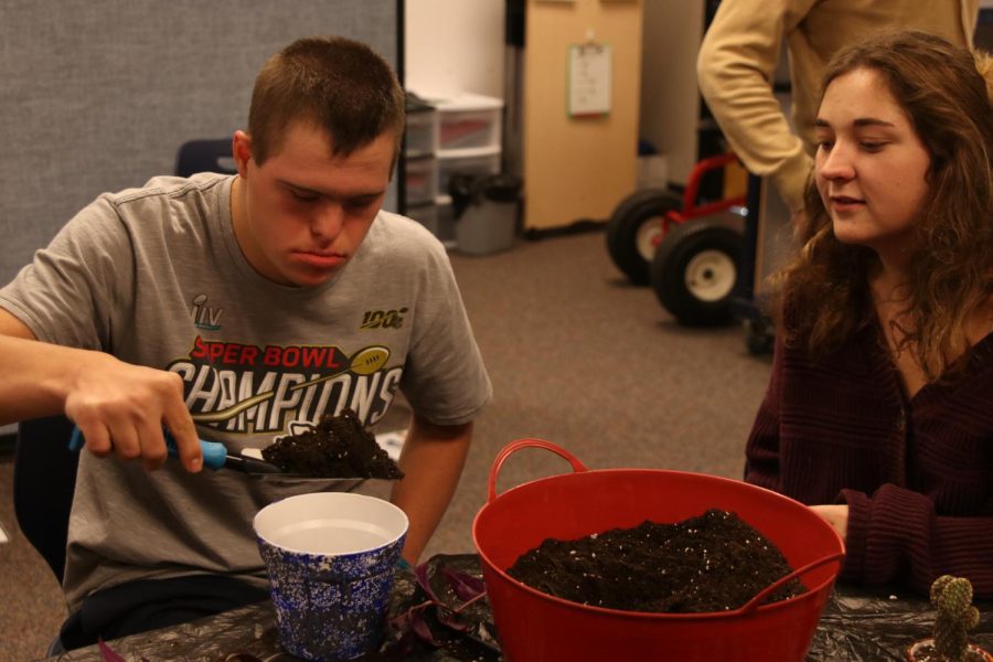 Senior Hannah McLeod watches as Senior Austin Tomandl shovels dirt into a plant pot
