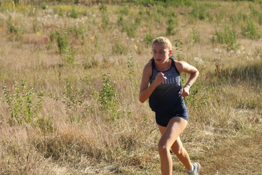 Coming up on the hill, sophomore Meg McAfee runs in the varsity race.