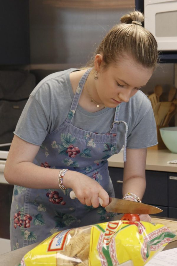 Focused on her next slice, senior Ava Cash cuts into the tomato. 