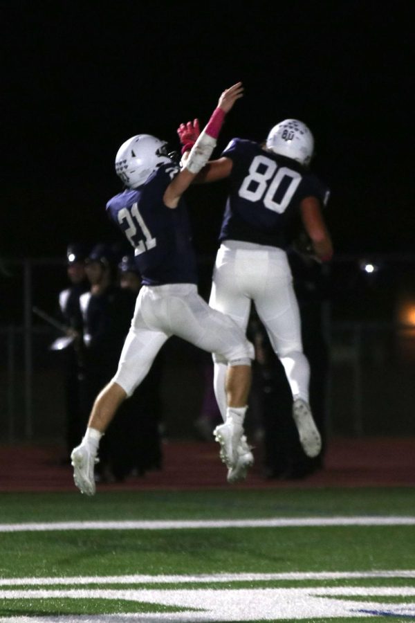 Junior Tristan Baker and sophomore Brody Brigham jump in the air after scoring a touchdown.