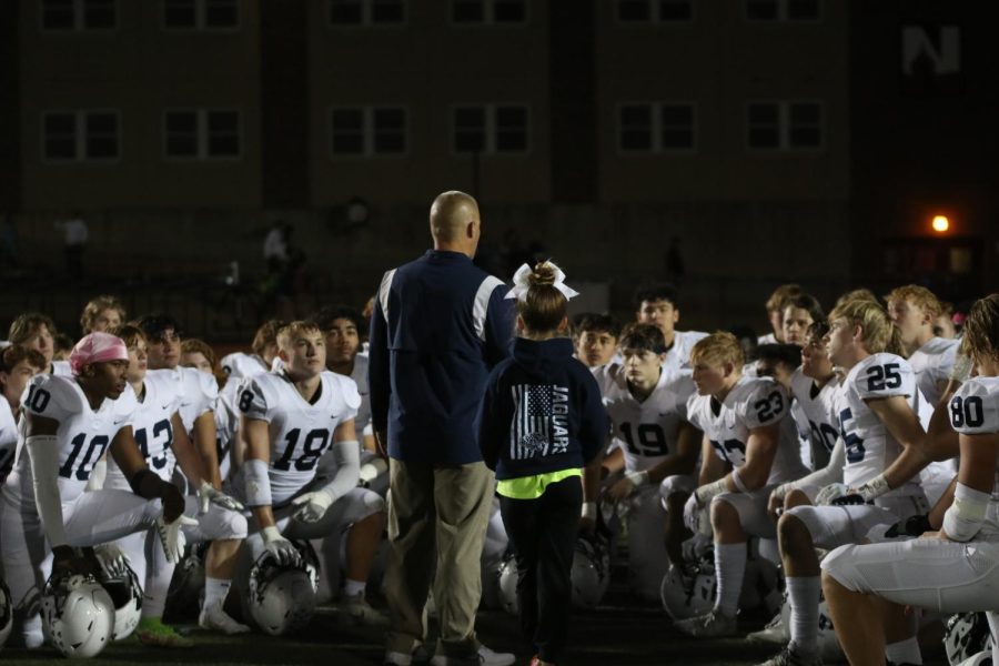 After a win with a score of 63-3, the Jaguars kneel on the field while listening to head coach Joel Applebee.