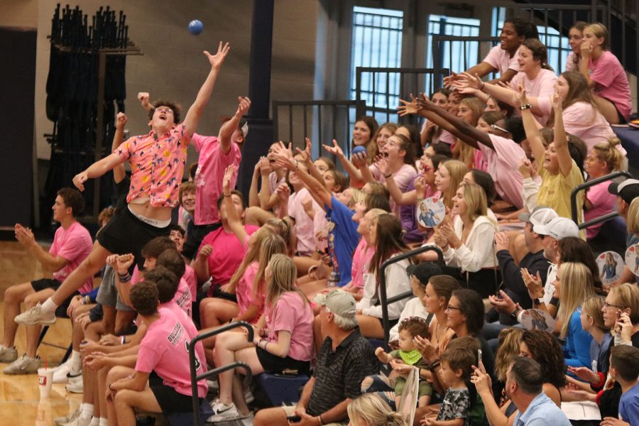 Students excitedly reach to catch a ball thrown by the Jag volleyball players on senior night.