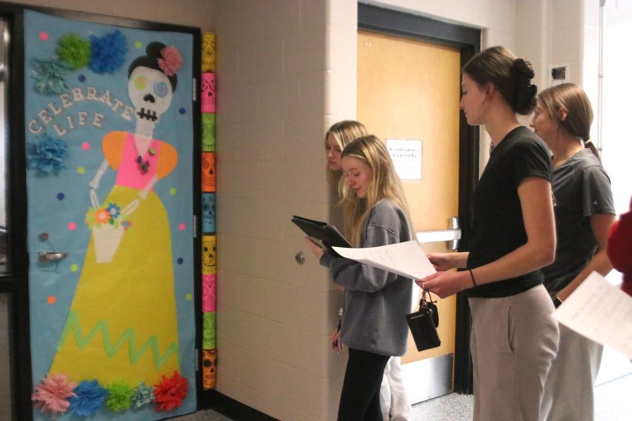 Evaluating Mrs. Dalbellos door, judges seniors Baylen Monson, Chloe Miller, and Natalie Merley praise the colorful composition of the door.