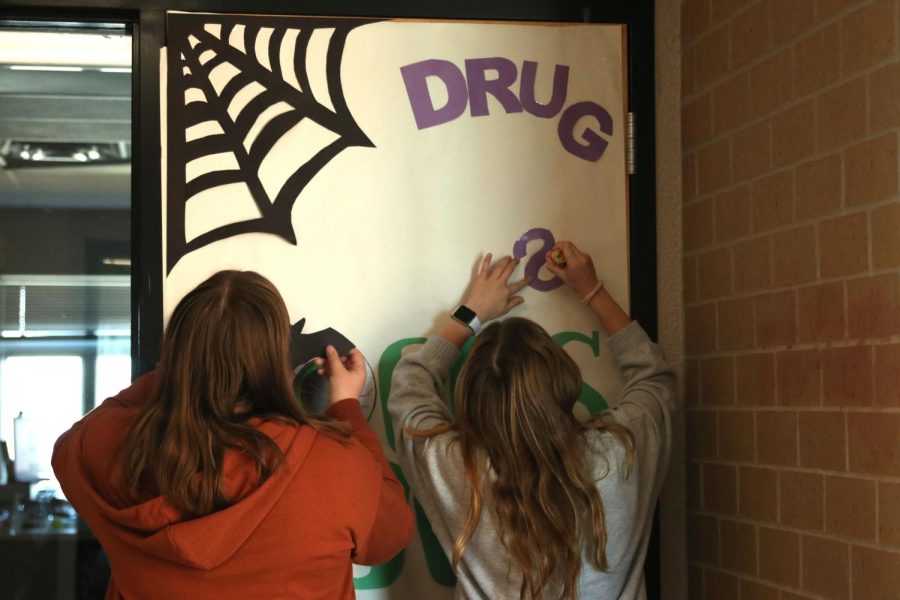 Freshmen Kaitlyn Shinkel and Isabelle Simms work hard to finish decorating Mr. Walden’s door on one of the last days to decorate for the competition.