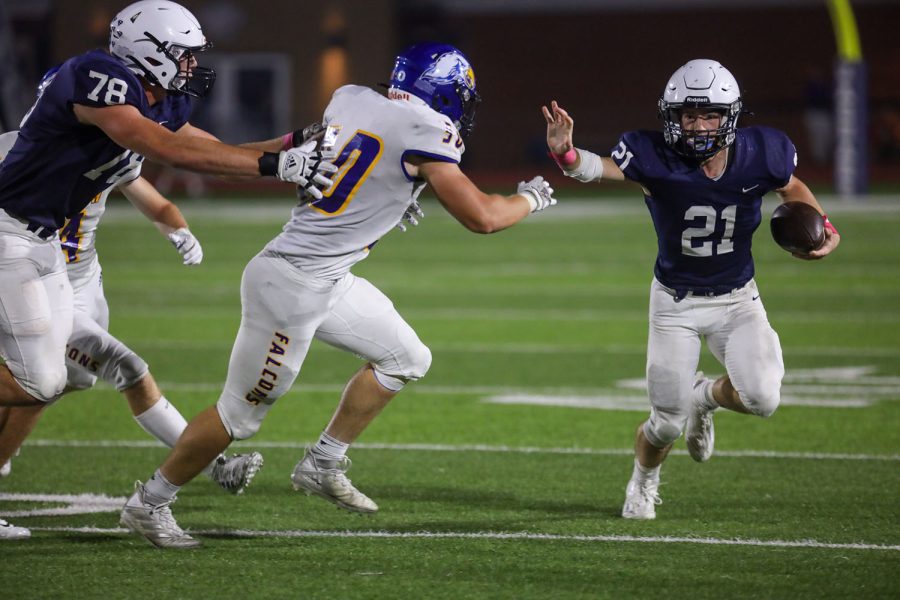 Holding his hand out in front of him, junior Tristan Baker tries to run down the line to  avoid the players beside him. 
