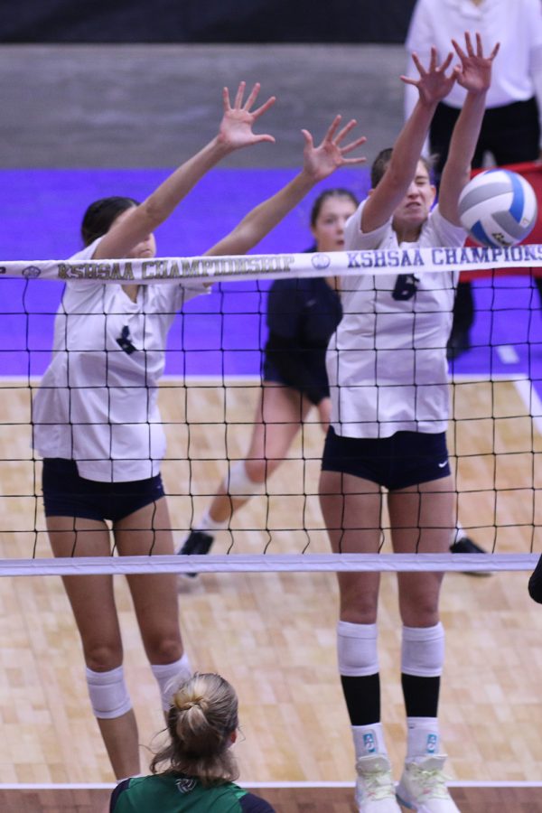 With arms outstretched, sophomore Ashlyn Blazer and junior Kaitlyn Burke stuff their Free State opponent during the 2-0 win in the second match of the state tournament.