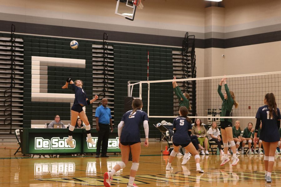 Showing off her vertical, junior Kaitlyn Burke hits the ball past the opposing blockers.

