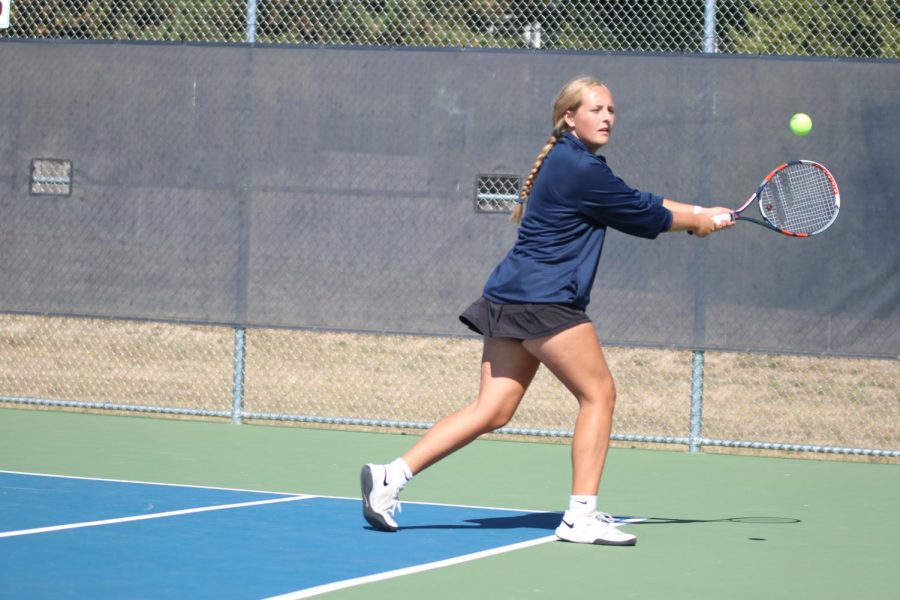 Running towards the ball, senior Avery Blubaugh hits the ball towards her opponent.
