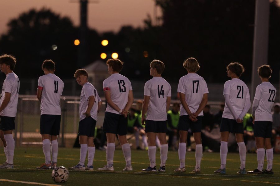 As a part of the pregame lineup, members of the boys soccer team stand at centerfield for the playing of the nation anthem.