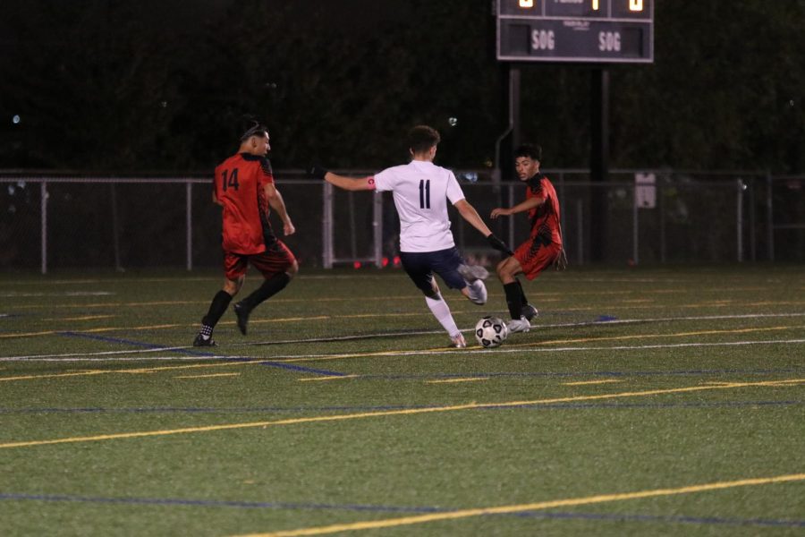 Senior Dylan Ashford takes a shot at the goal between two Shawnee Mission North defenders. 